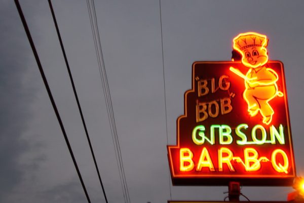 Neon sign for Big Gibson Bar-B-Q amid gray sky