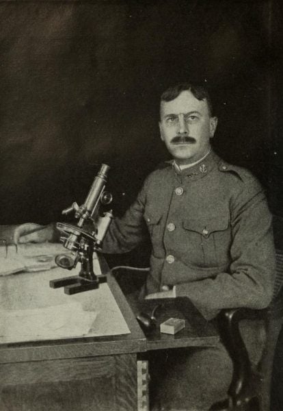 Charles Wardell Stiles, seated at microscope